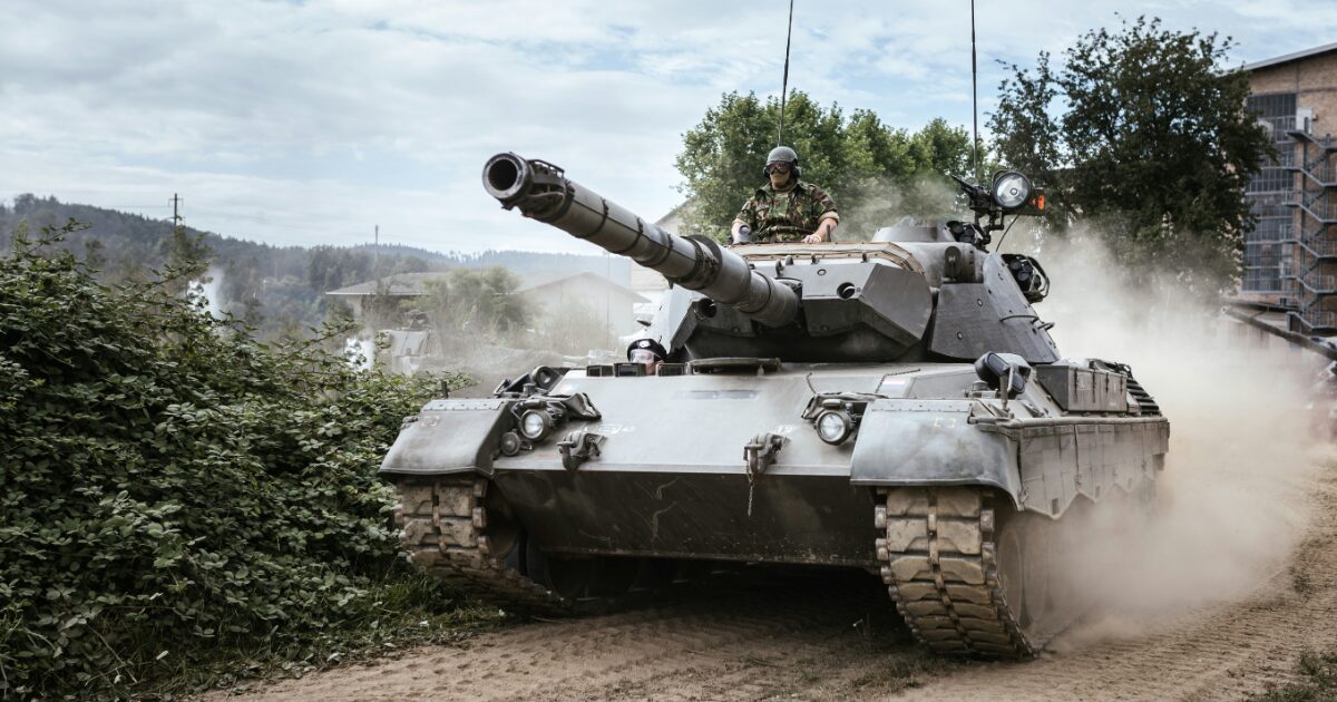 未舗装路を走行する戦車と搭乗する兵士