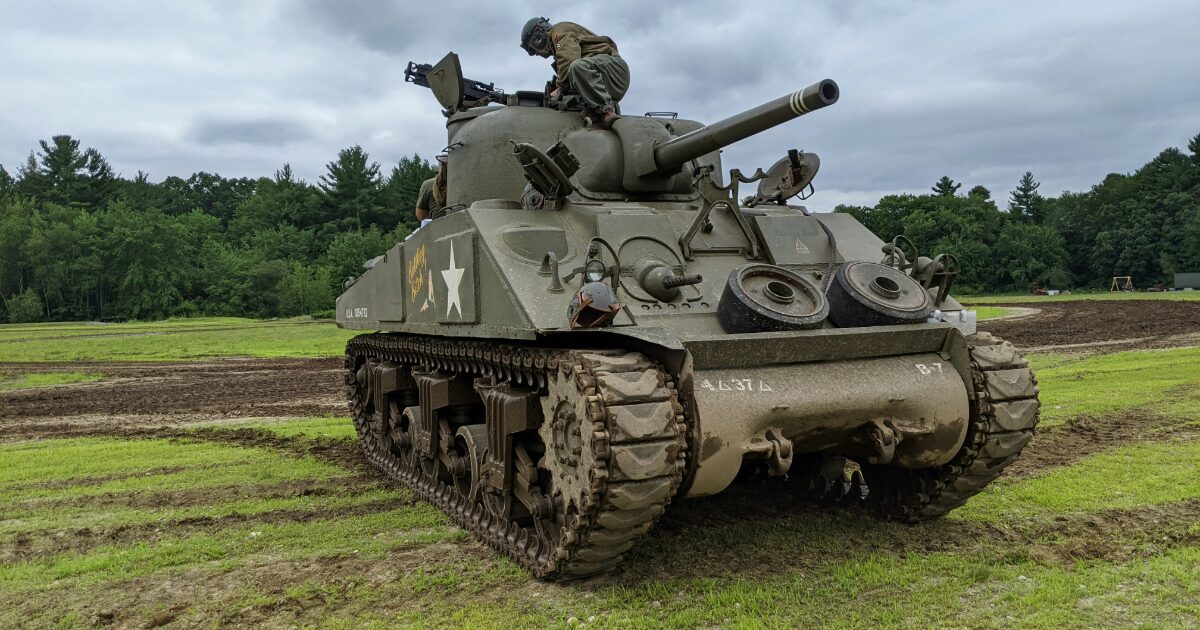 草地に停車した戦車と整備作業を行う兵士