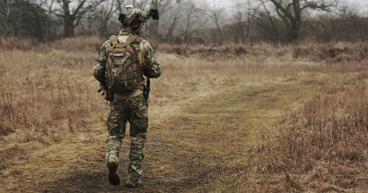野外で巡回任務を行う装備を着用した兵士の後ろ姿